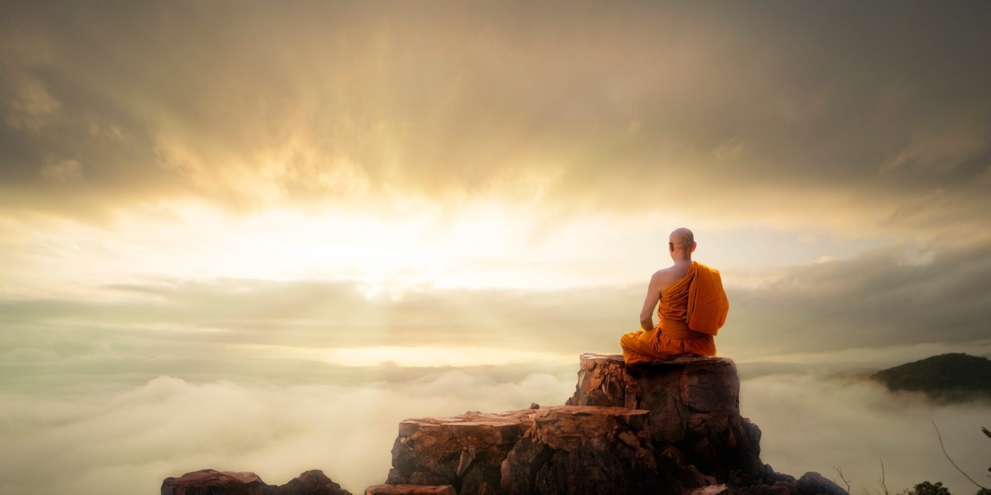 Buddhist monk in meditation at beautiful sunset or sunrise background on high mountain