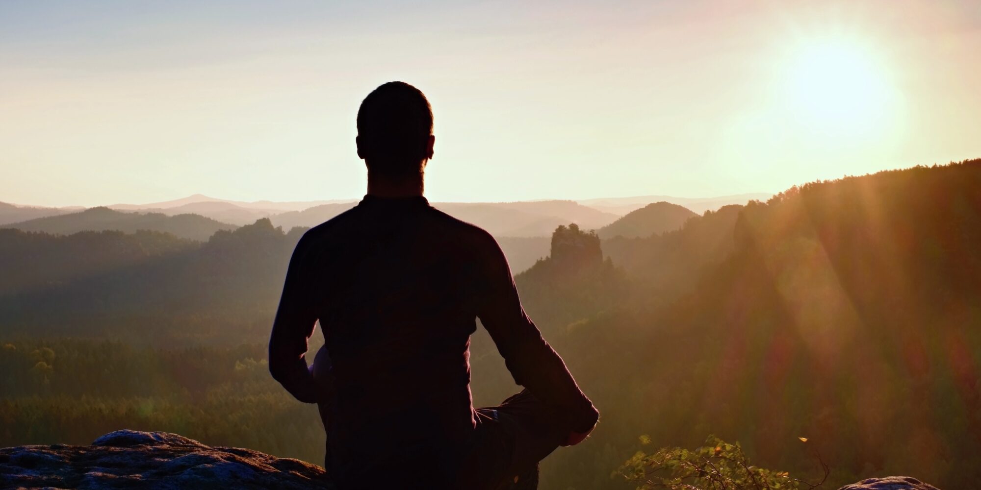 Hiker in squatting position on a rock, enjoy the scenery